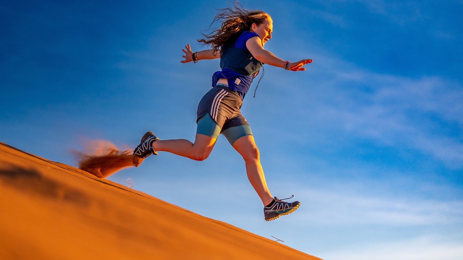 An athlete running down a desert dune
